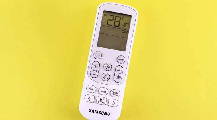 Air conditioner remote with temperature set at 28°C on a yellow background