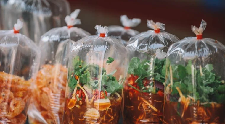 Colorful Thai street food neatly packaged in transparent bags at a Bangkok market