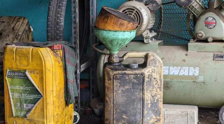 A worn metal drum and vintage compressor in an industrial workshop setting, exuding a classic and rustic feel