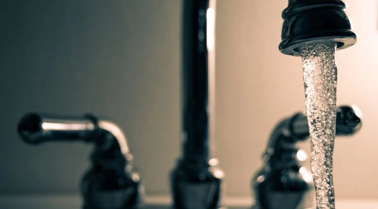 A detailed shot of water flowing from a steel faucet, ideal for themes on cleanliness or plumbing
