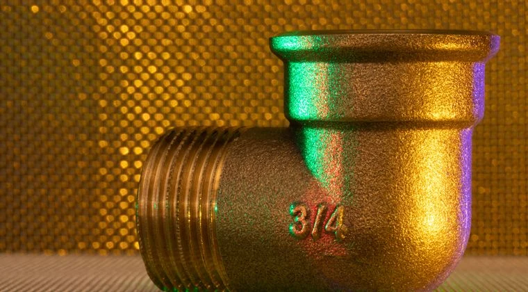 A golden 3/4 inch pipe fitting against an elegant, textured, golden backdrop