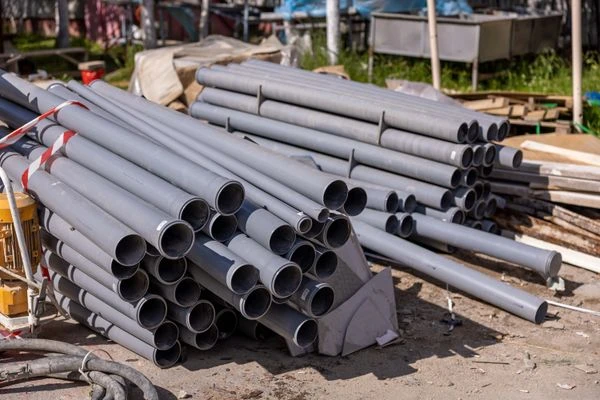 A collection of gray PVC pipes neatly stacked at an outdoor construction site