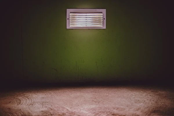 Moody room with a ventilation grate on a textured green wall