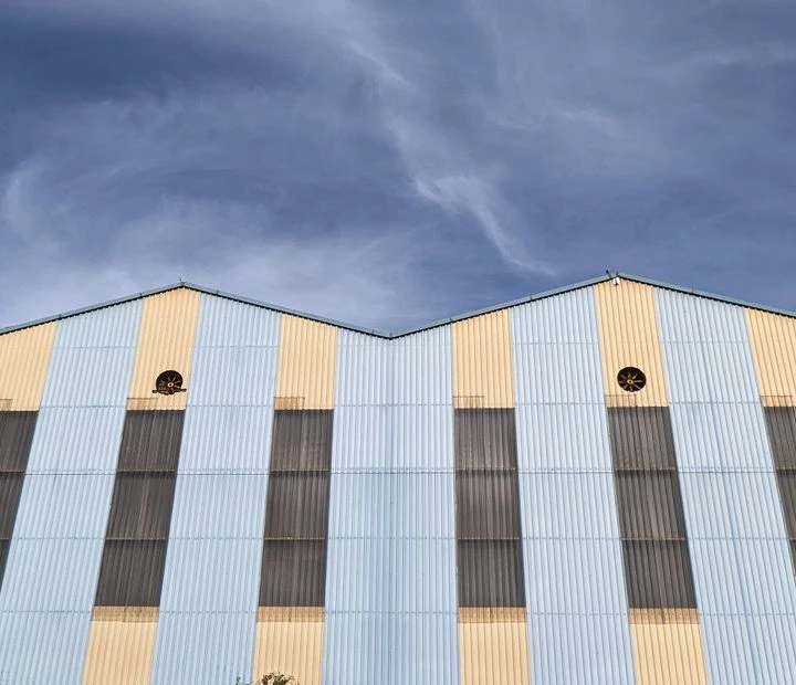 Colorful industrial building facade against clear blue sky, featuring large windows