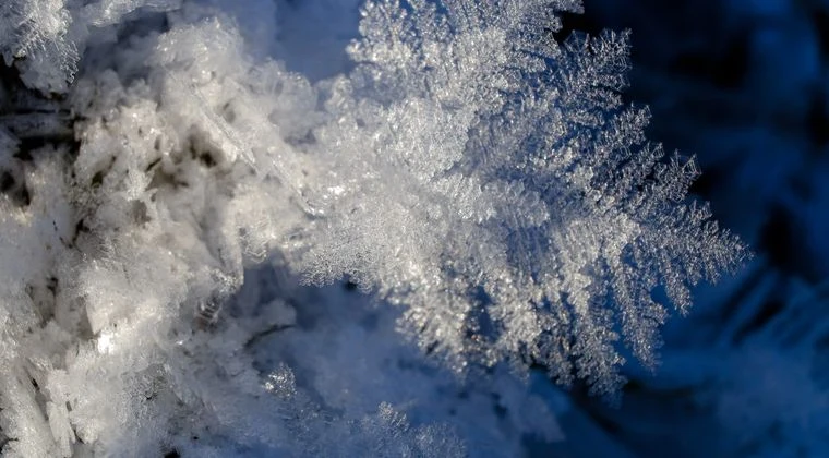 A macro photograph capturing the intricate details of a frosted snowflake on a cold winter day